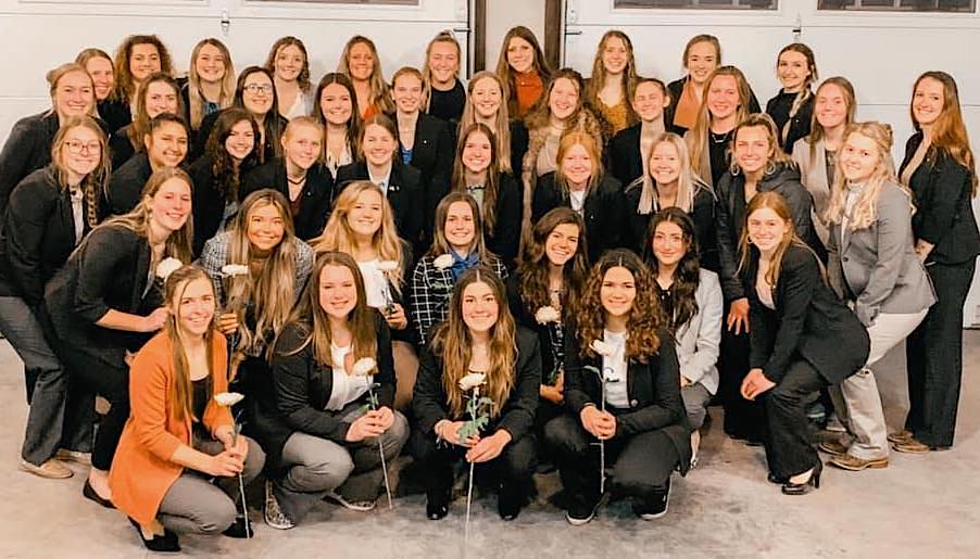 a large group of young women holding flowers