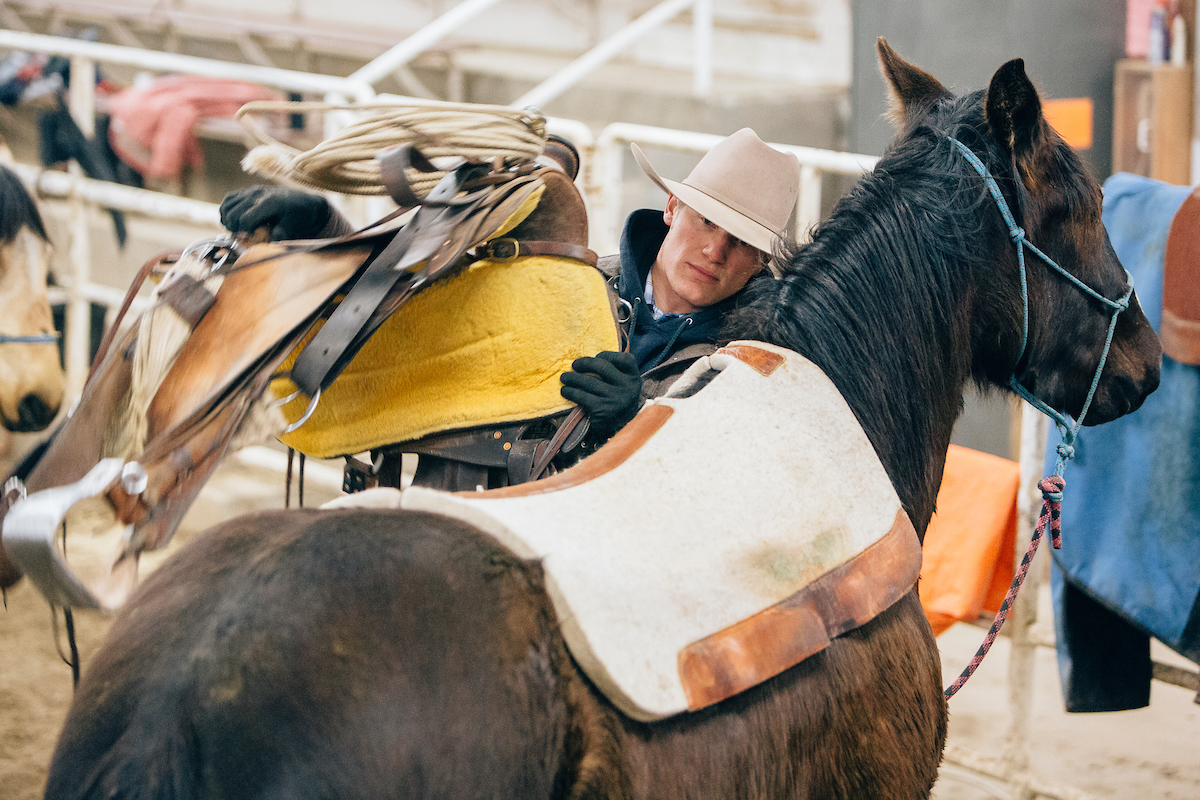 young man saddling a horse