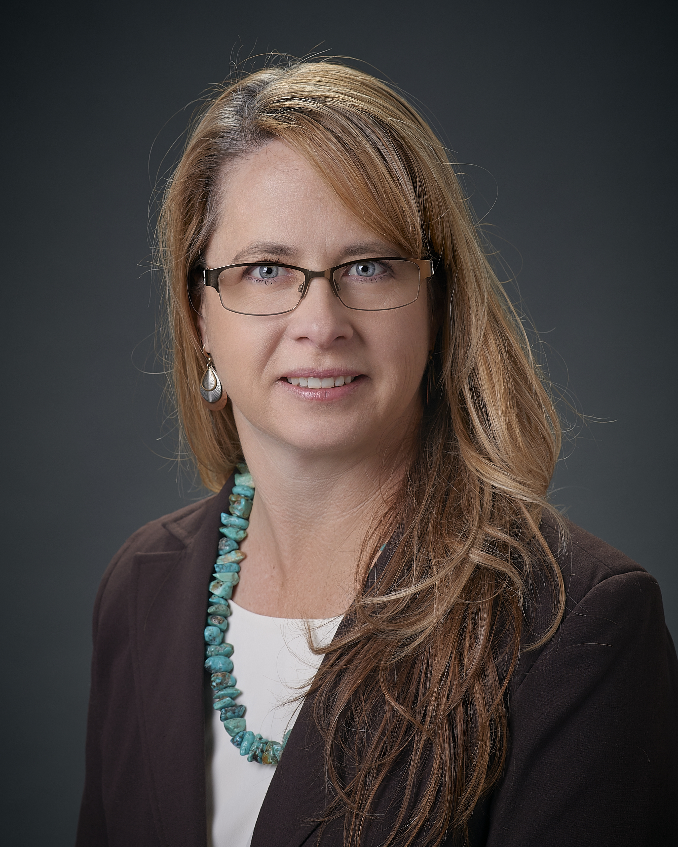 a woman with long golden hair and sideswept bangs, wearing glasses